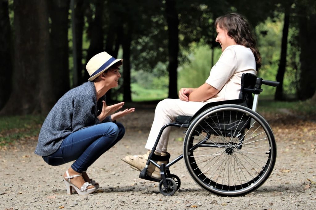 person talking expressively to person in wheelchair